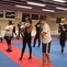 Gruppe von Jugendlichen in Sportkleidung &uuml;bt Boxtechniken in einem Trainingsraum mit blauen und roten Matten.