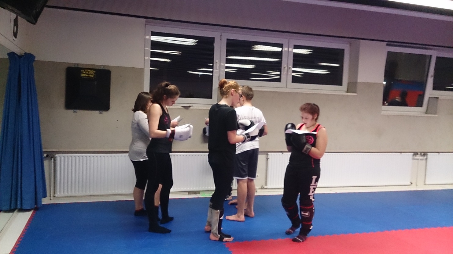 Gruppe von Sportlern in einem Trainingsraum, die Boxhandschuhe tragen und sich auf eine &Uuml;bung vorbereiten.