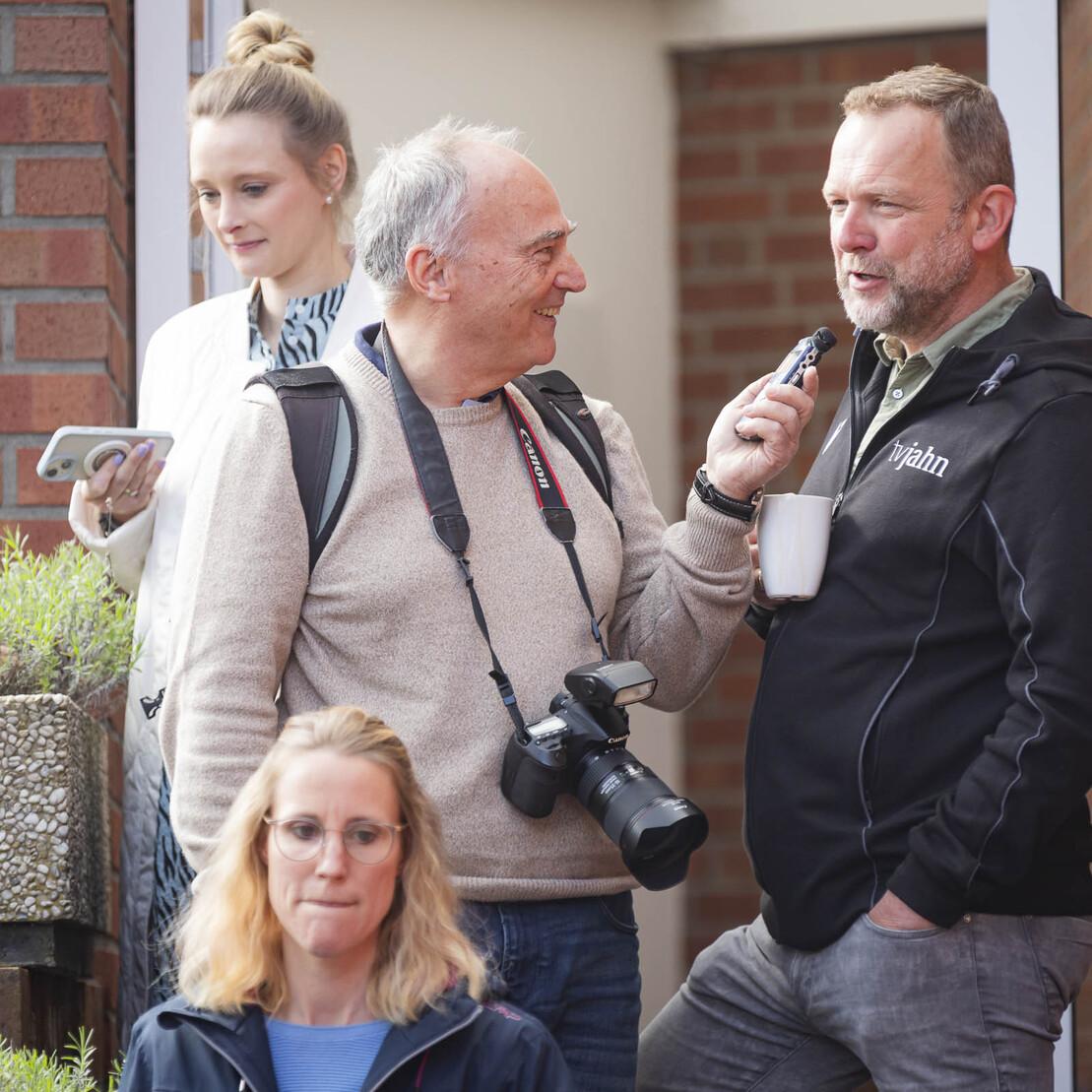 Vier Personen stehen vor einem Geb&auml;ude, zwei unterhalten sich, w&auml;hrend eine Frau auf ihr Smartphone schaut.