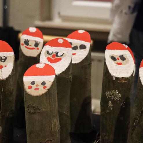 Bunt bemalte Holzst&auml;mme mit Weihnachtsmann-Gesichtern stehen auf einem Tisch.