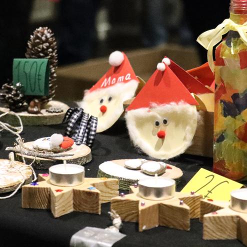 Bunte Weihnachtsdekorationen auf einem Tisch, darunter Wichtelgesichter und Kerzen auf Holzunterlagen.