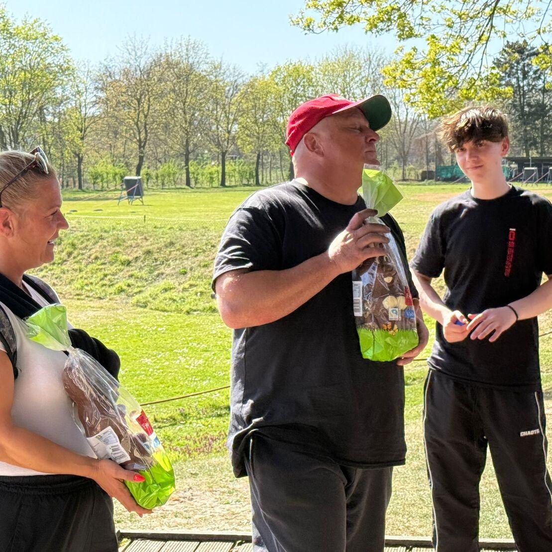 Drei Menschen stehen im Freien und halten Geschenkt&uuml;ten mit S&uuml;&szlig;igkeiten in der Hand, umgeben von Natur.