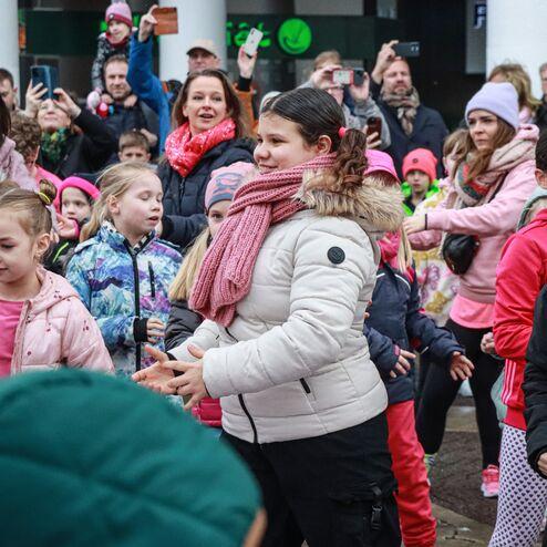 Eine Gruppe von Kindern und Erwachsenen tanzt fr&ouml;hlich bei einer Veranstaltung im Freien.