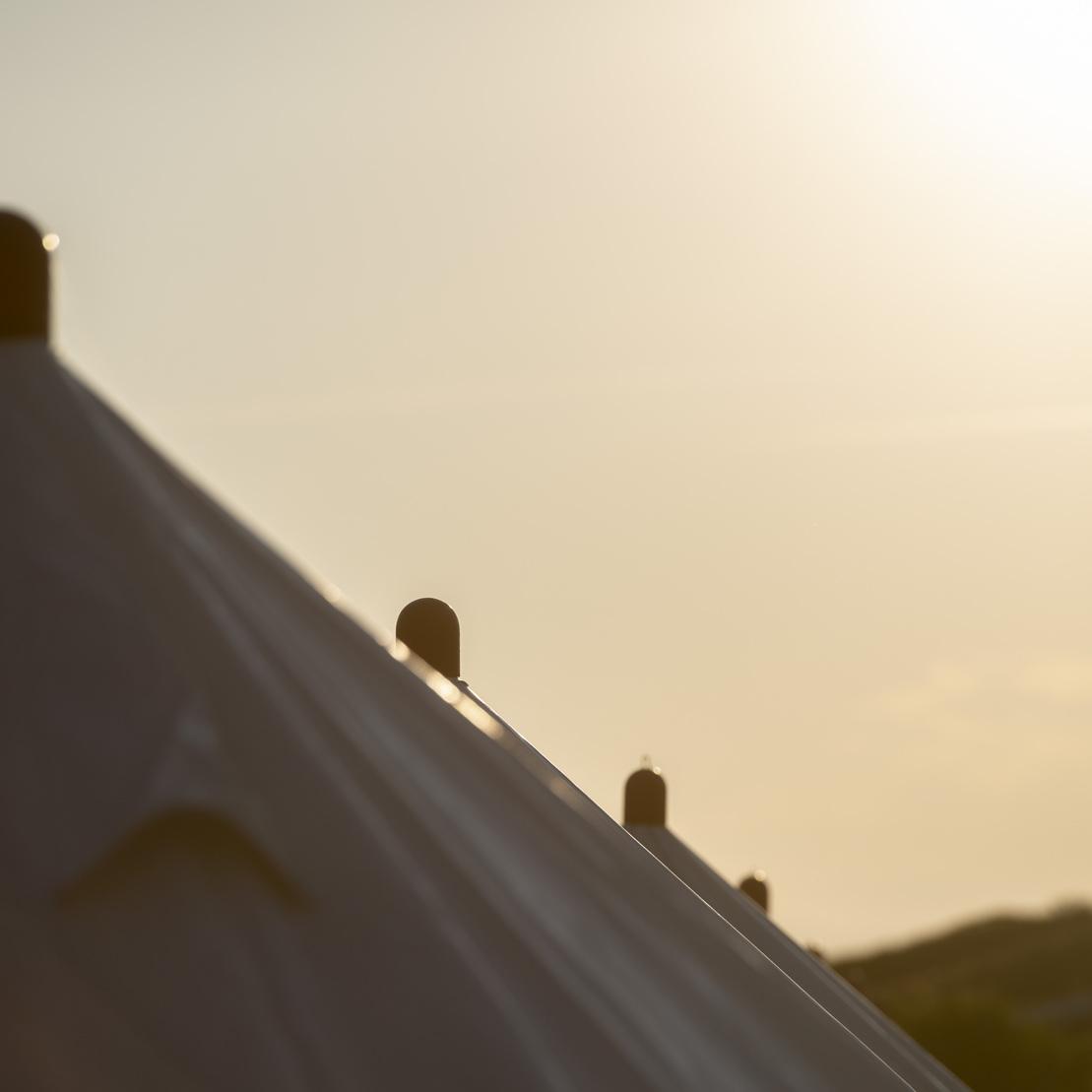 Dachansicht von einem Zelt mit sonnigem Hintergrund und sanften Lichtverlauf am Himmel.