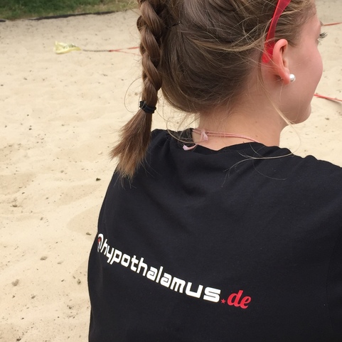 Nahaufnahme des hinteren Teils eines M&auml;dchens mit braiding Haar, das ein schwarzes T-Shirt mit der Aufschrift "hypothalamus.de" tr&auml;gt.