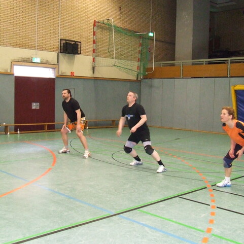 Drei M&auml;nner in Sportkleidung stehen auf einer Sporthalle und bereiten sich auf ein Spiel in der Mitte des Feldes vor.