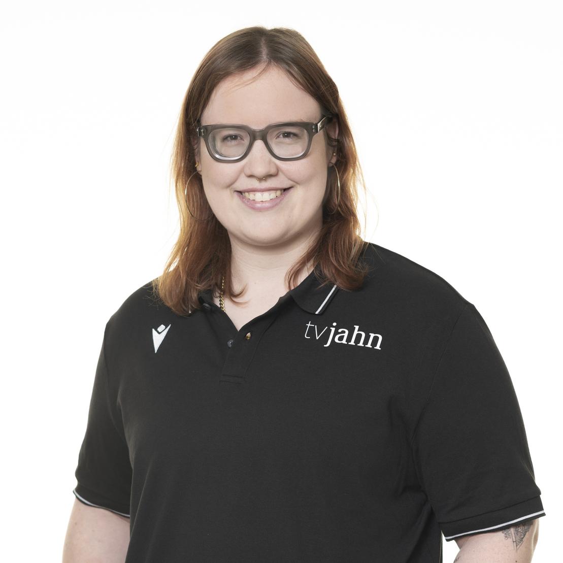 Porträt einer lächelnden Person mit Brille, die ein schwarzes Poloshirt mit dem Aufdruck „tvjahn“ trägt.