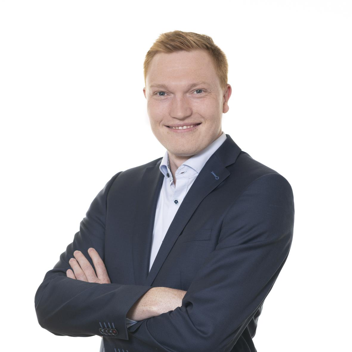 Junger Mann in Anzug mit verschr&auml;nkten Armen vor wei&szlig;em Hintergrund.