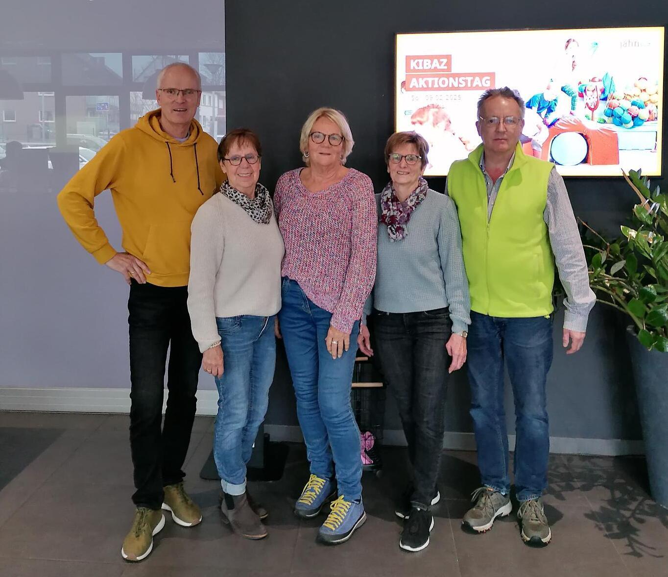 Gruppenshot von fünf Personen vor einer Wand mit einem Bildschirm, auf dem "KIBAZ Aktionstag" steht.