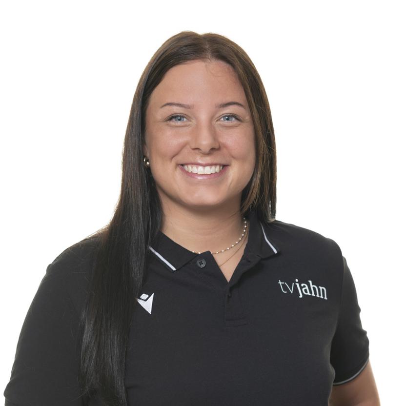 Porträt einer lächelnden Frau mit langen, dunklen Haaren, die ein schwarzes Poloshirt mit Logo trägt.