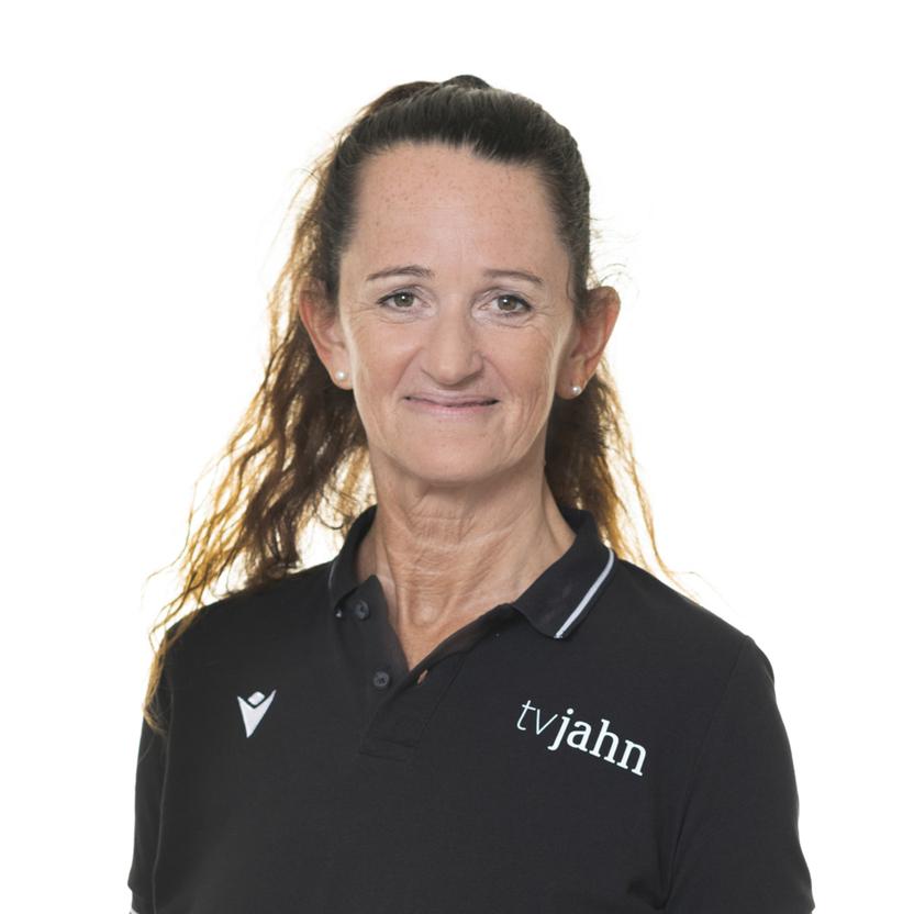 Frau mit langen, lockigen Haaren trägt ein schwarzes Poloshirt mit dem Aufdruck „tv jahn“. Neutraler Hintergrund.