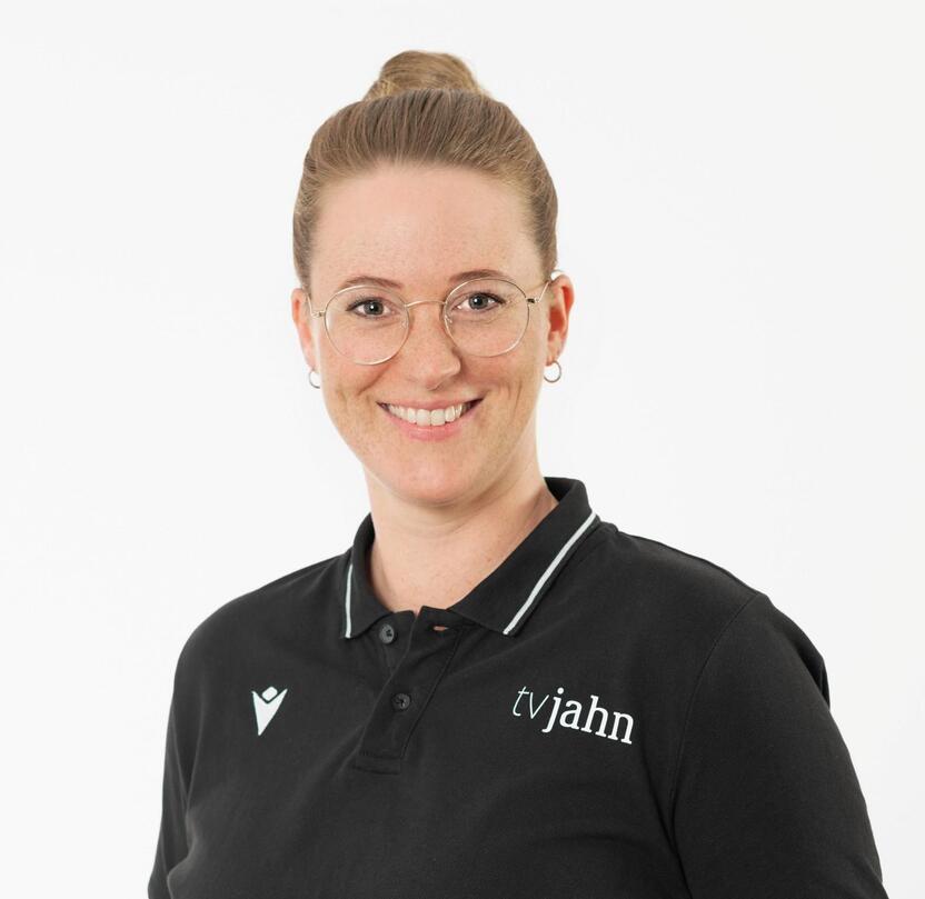 Portr&auml;t einer l&auml;chelnden Frau in schwarzem Poloshirt mit Logo, stehen vor wei&szlig;em Hintergrund.