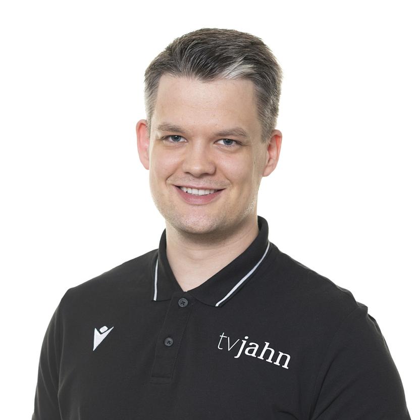 Lächelnder Mann in schwarzem Polo-Shirt mit Logo auf weißem Hintergrund.