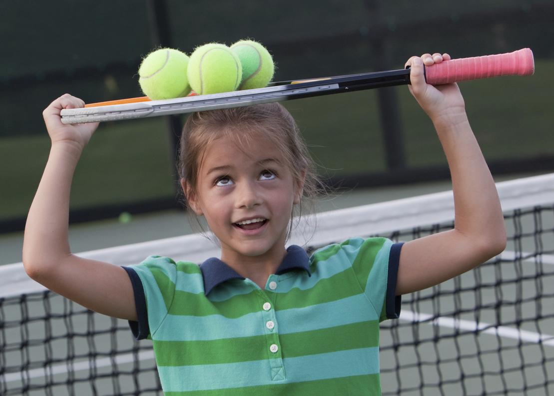 Mädchen mit gestreiftem Shirt hält einen Tennisschläger über dem Kopf, darauf liegen drei Tennisbälle.