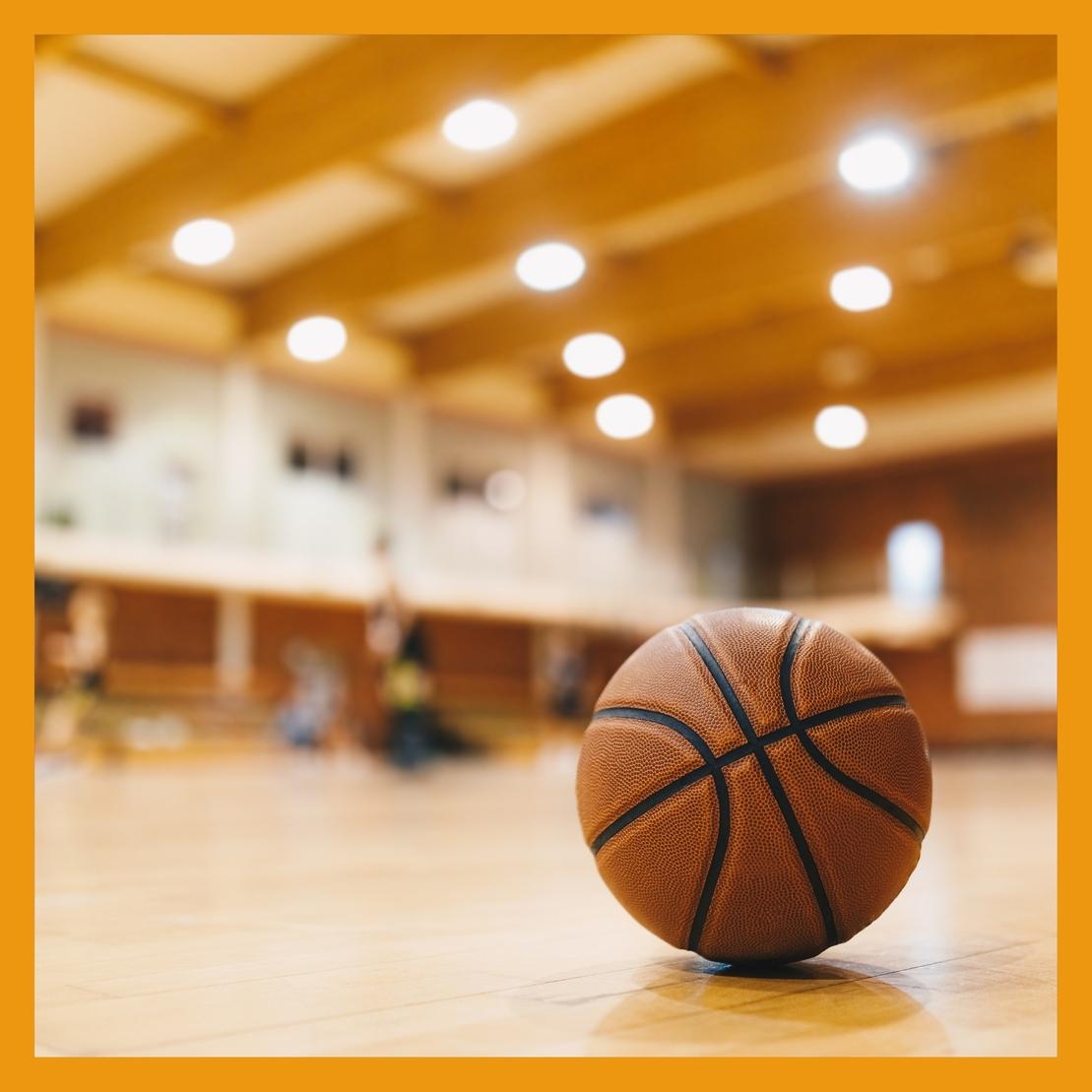 Nahaufnahme eines Basketballs auf einem Holzparkettboden in einer Sporthalle.