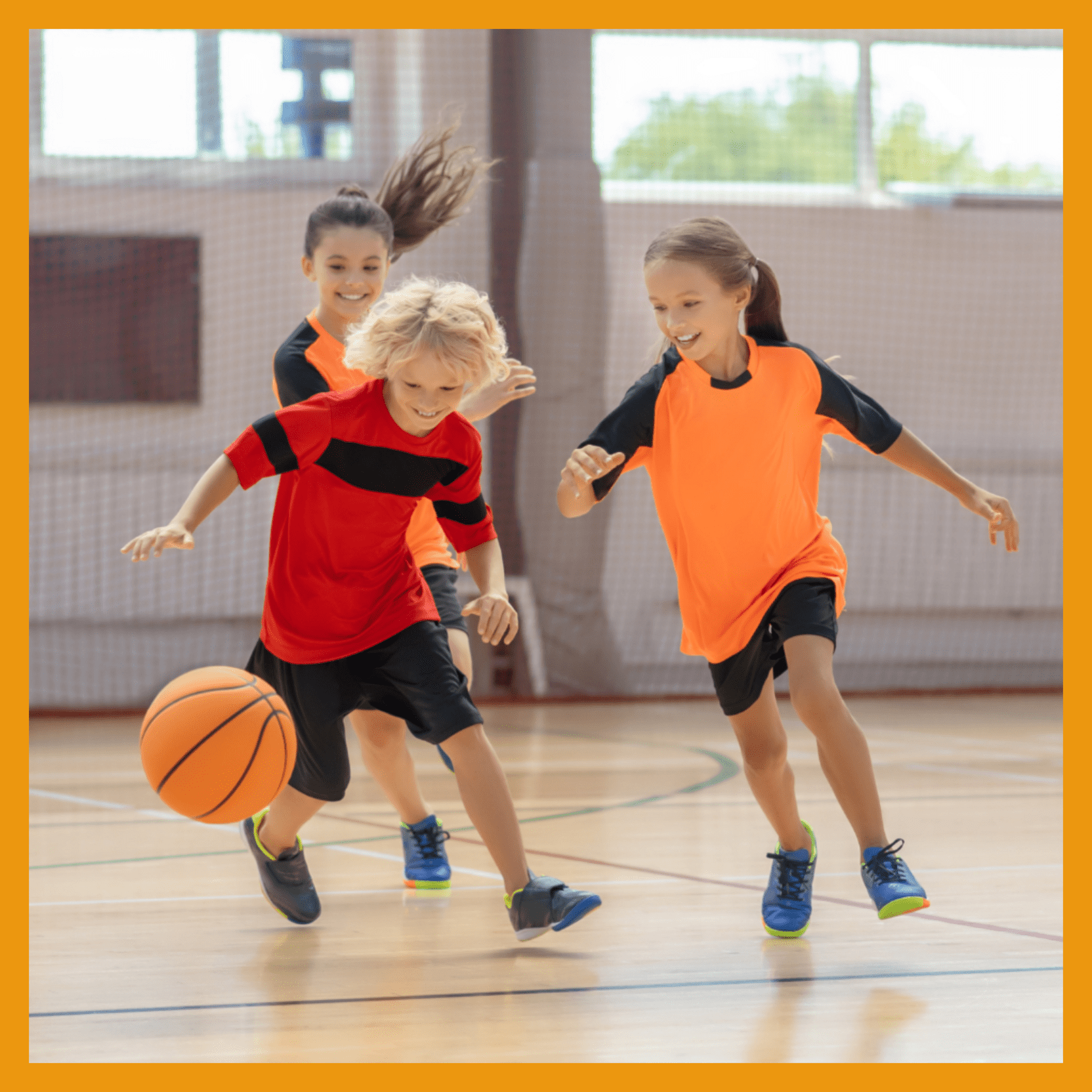 Drei Kinder in Sportkleidung spielen im Gymnastikraum mit einem Basketball.