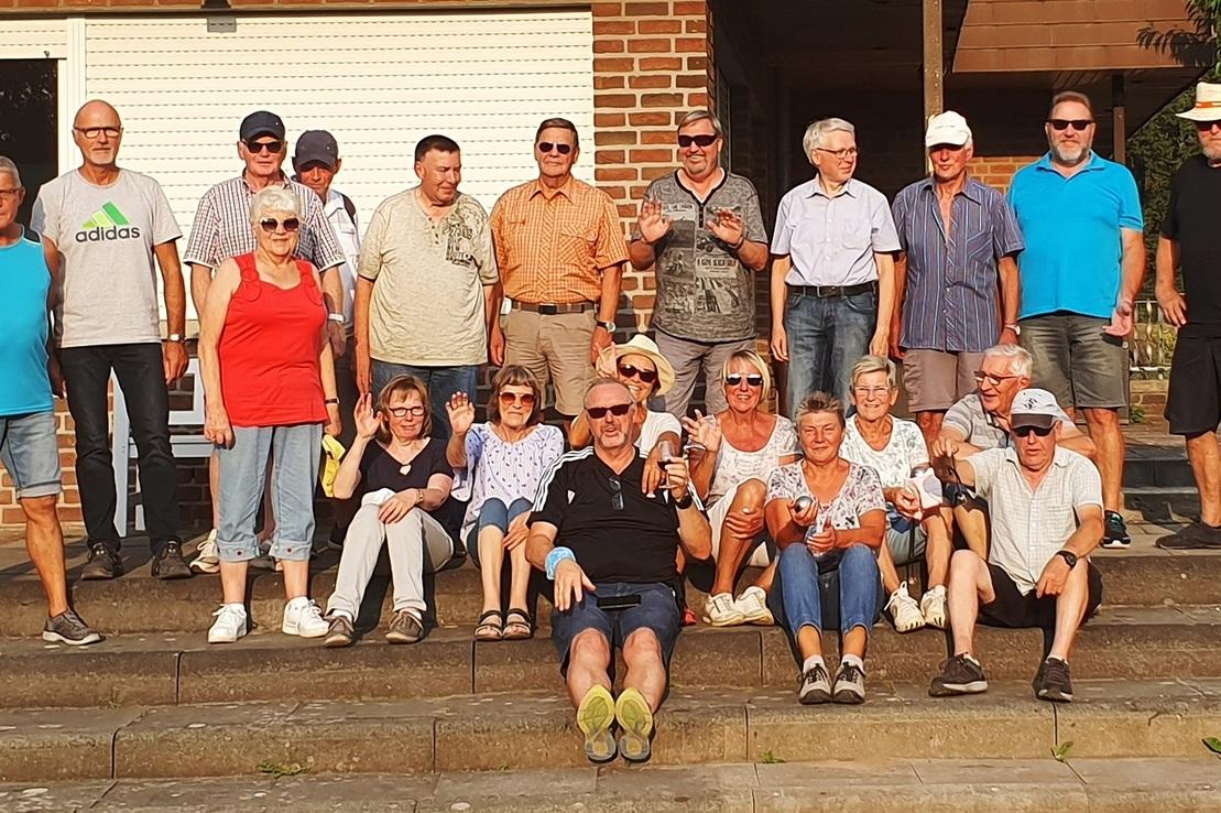 Gruppenfoto von 20 Personen auf einer Treppe vor einem Geb&auml;ude, alle l&auml;cheln und posieren in freizeitlicher Kleidung.
