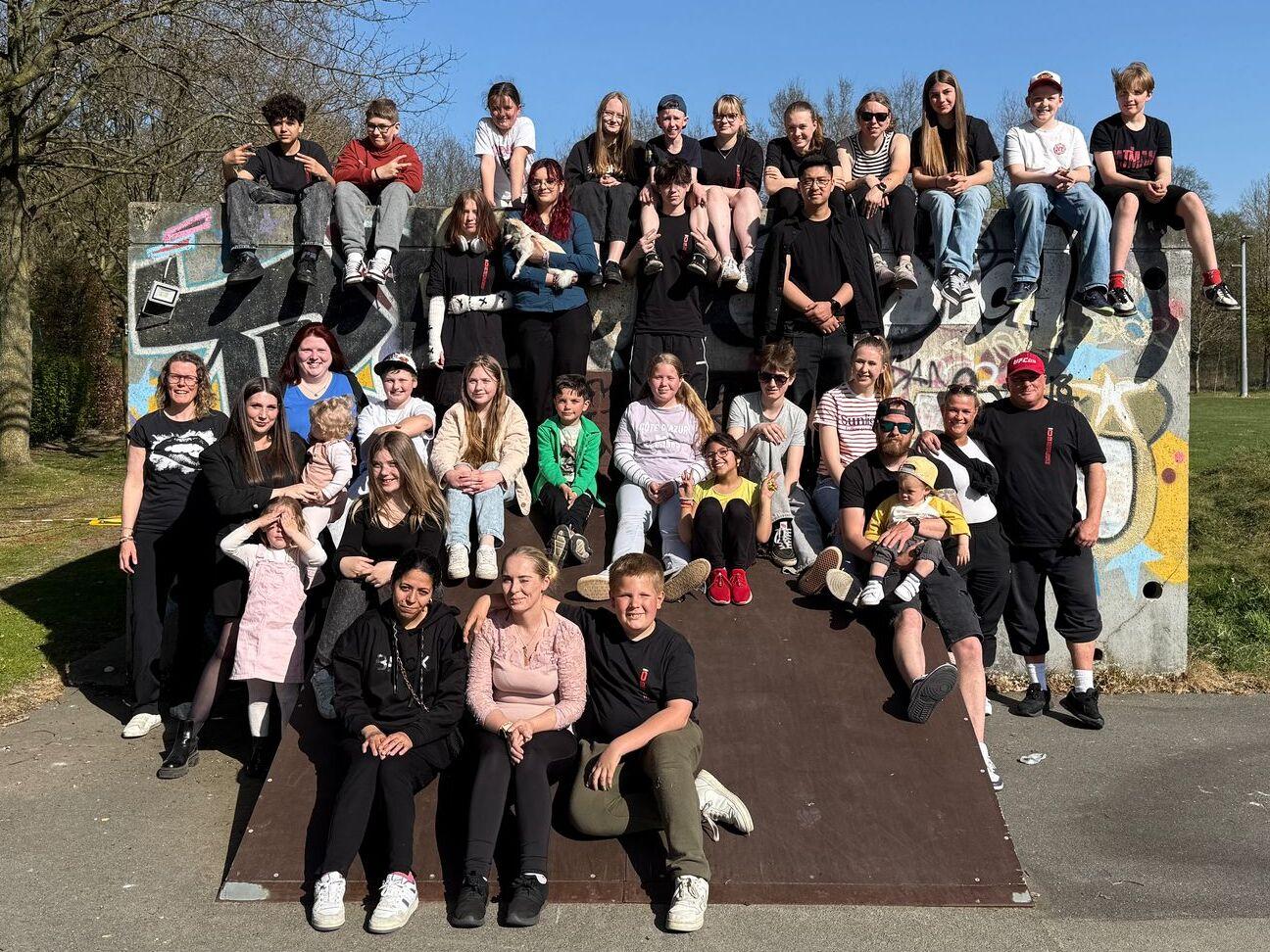 Gruppenfoto von etwa 40 Jugendlichen auf einem Kletterturm im Park bei blauem Himmel und Bäumen im Hintergrund.