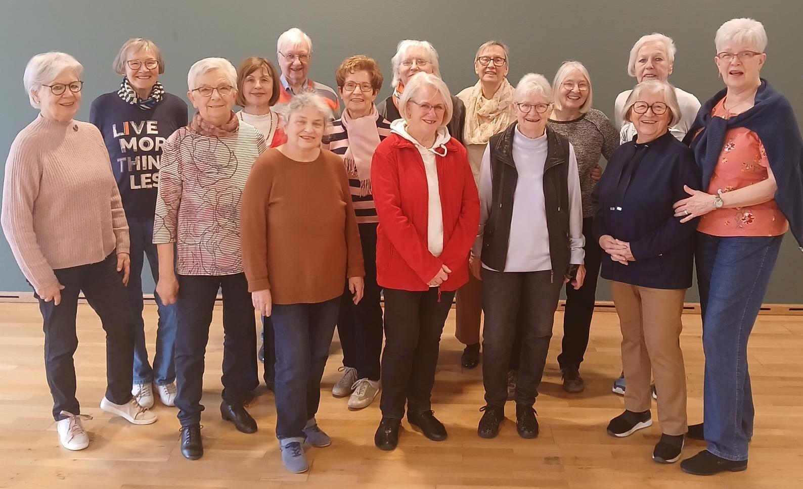 Gruppenshot von 17 &auml;lteren Frauen in einem Raum mit fr&ouml;hlichen Gesichtsausdr&uuml;cken und unterschiedlichen Kleidungsstilen.