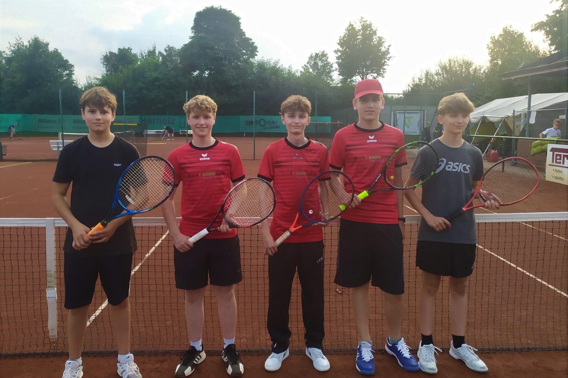 F&uuml;nf Jugendliche mit Tennisschl&auml;gern stehen auf einem Tennisplatz, im Hintergrund sind Tennisnetze und Umrandungen sichtbar.