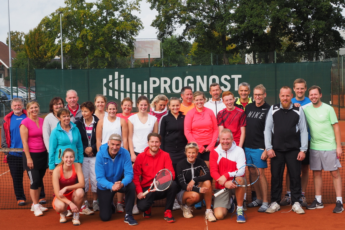 Gruppenfoto von etwa 30 Personen in Sportkleidung auf einem Tennisplatz vor einem PROGNOST-Werbeschild.
