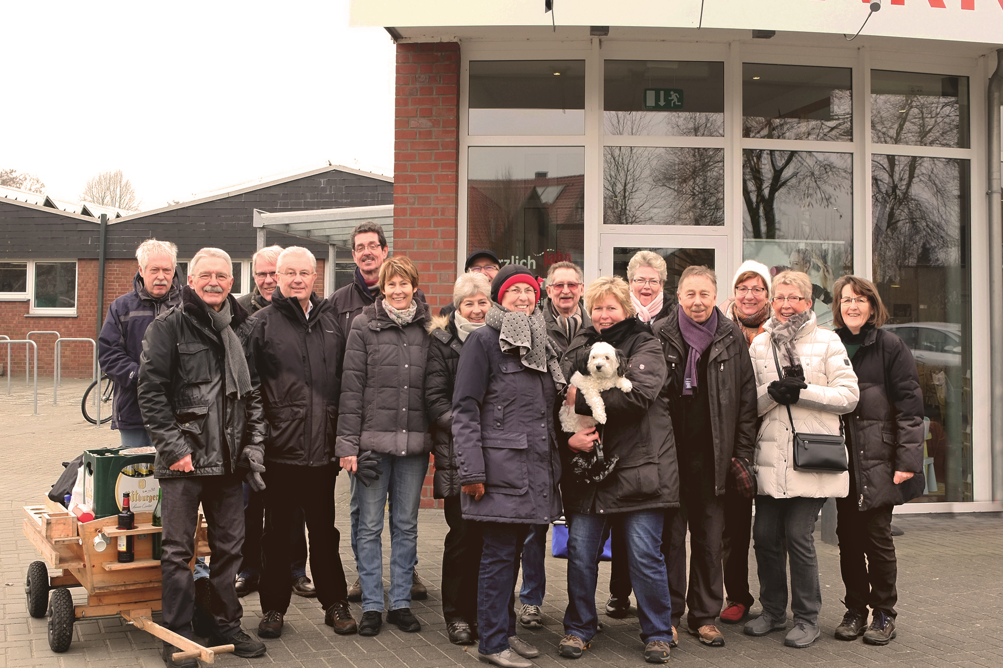 Gruppe von 15 Personen steht l&auml;chelnd vor dem Sportpark-Eingang, einige halten einen kleinen Hund und einen Bollerwagen.